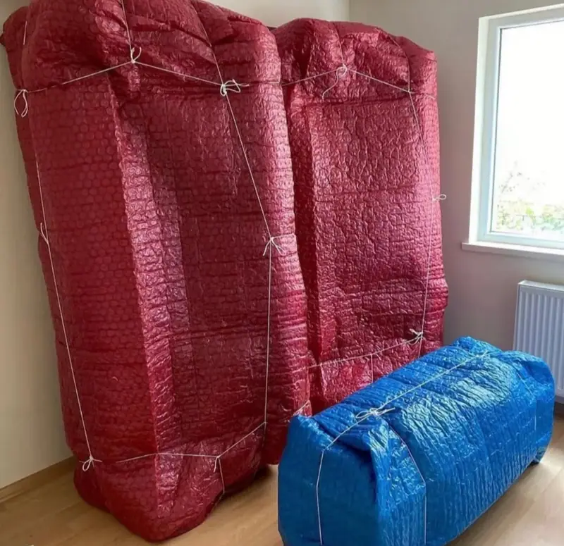 İki gardırop kırmızı, yatak mavi balonlu naylonla paketlenmiş ve iple sabitlenmiş